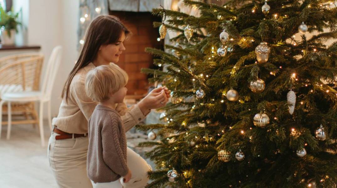 Μαμά και παιδί στολίζουν το χριστουγεννιάτικο δέντρο