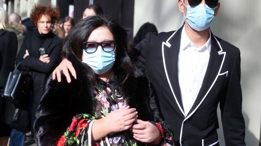 Άνδρας και γυναίκα με προστατευτικές μάσκες στην Εβδομάδα Μόδας του Μιλάνου