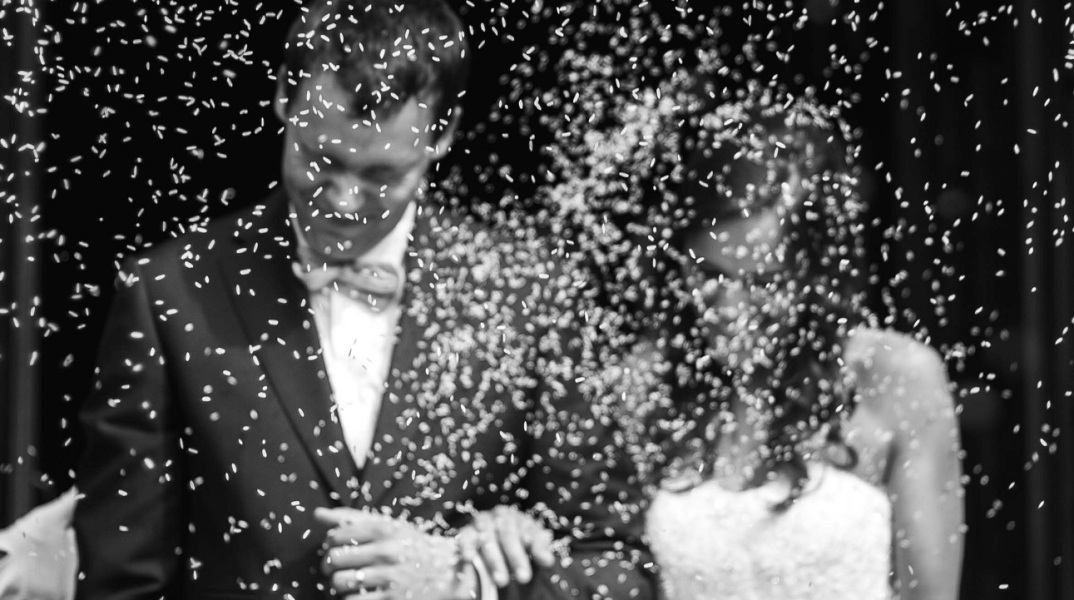 Ασπρόμαυρη φωτογραφία με ζευγάρι που παντρεύται και του πετάνε ρύζι