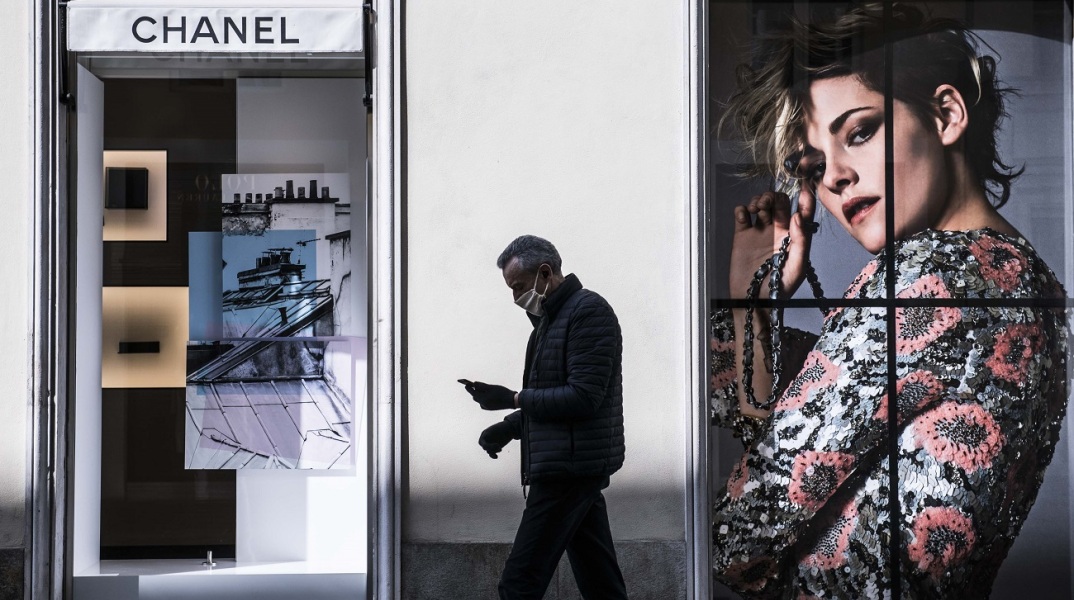 Άντρας με προστατευτική μάσκα περνάει έξω από κατάστημα Chanel