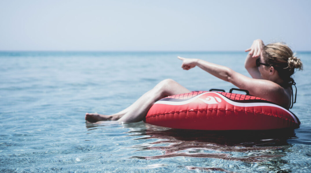 Γυναίκα κάθεται σε φουσκωτή κουλούρα στην θάλασσα