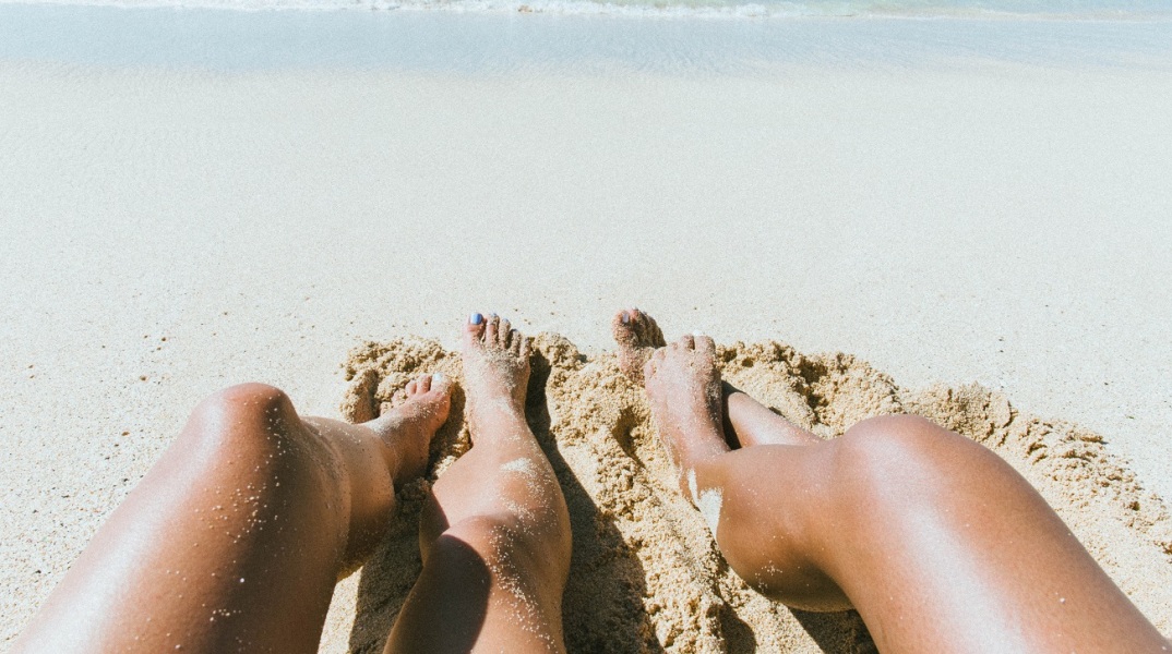 Γυναικεία πόδια στην άμμο παραλίας