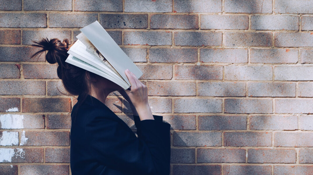 Κοπέλα με βιβλίο ακουμπισμένο στο πρόσωπό της