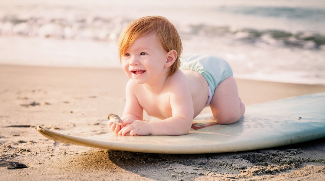 Μωρό σε σανίδα του σερφ στην παραλία
