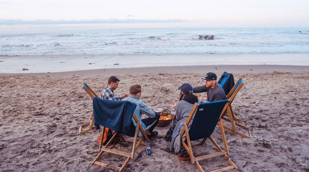 Τέσσερις φίλοι κάθονται σε καρέκλες στην παραλία
