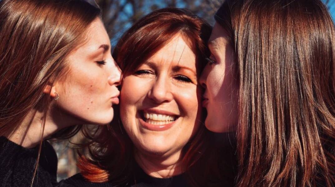 Δύο κόρες φιλάνε τη μητέρα τους στο μάγουλο