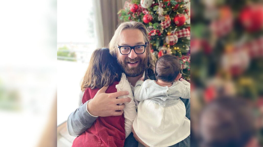 Ο Ευρυπίδης Γουργουλίδης αγκαλιά με τα δύο παιδιά του μπροστά από ένα χριστουγεννιάτικο στολισμένο δέντρο