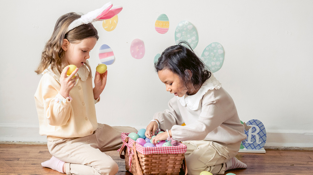 Δύο μικρά κορίτσια παίζουν με πασχαλινά αυγά