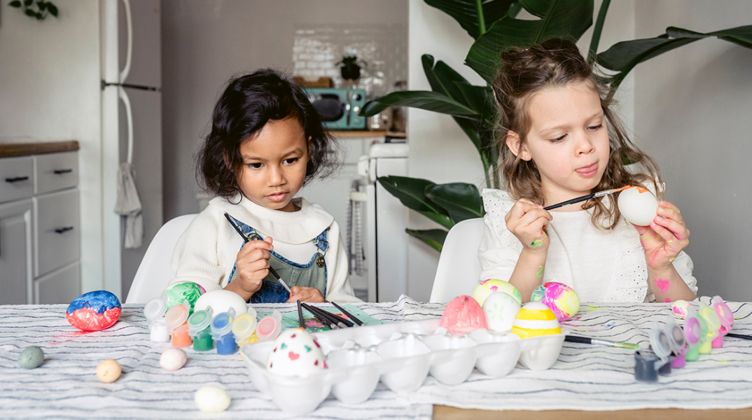 Δύο μικρά κοριτσάκια βάφουν πασχαλινά αυγά
