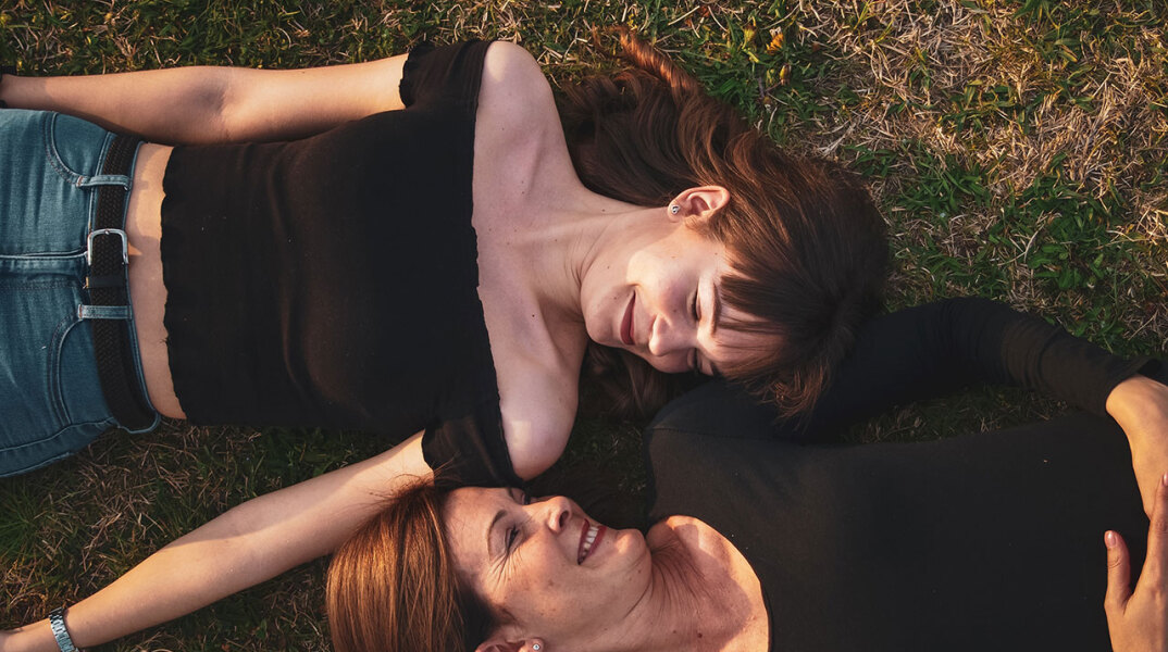 Δύο γυναίκες με μαύρα ρούχα ξαπλωμένες στο γρασίδι αντικριστά