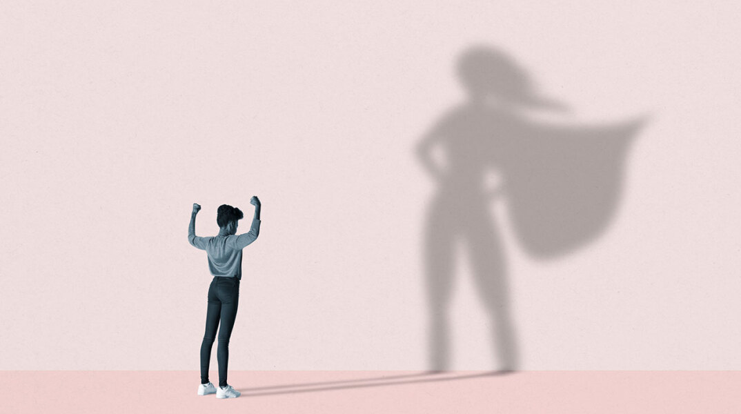 Εικονογράφηση γυναίκα που η σκιά της στον τοίχο έχει τη πόζα σουπερήρωα (μετα χέρια στη μέση και την κάπα να ανεμίζει)