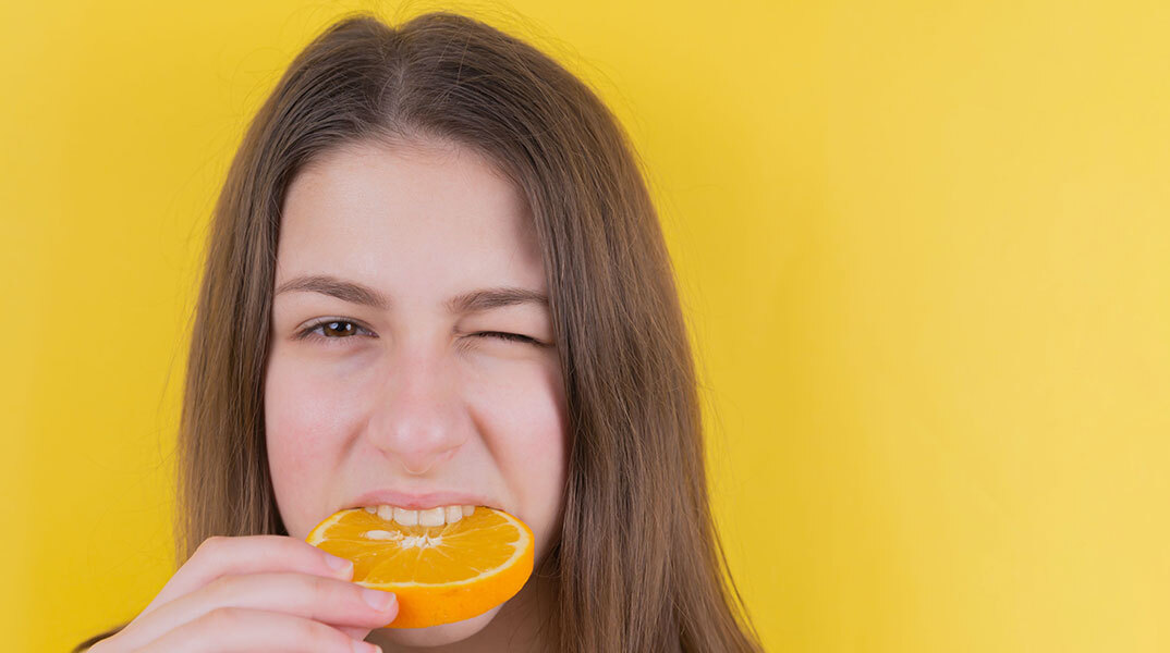 Κοπέλα δαγκώνει πορτοκάλι