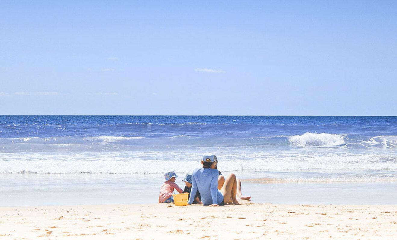 Οικογένεια κάθεται στην παραλία στην αμμουδιά