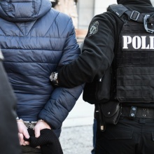 Άτομο που φορά χειροπέδες και κρατείται από αστυνομικούς