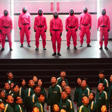 Άνθρωποι με κόκκινες και πράσινες στολές - Σκηνή από τη σειρά Squid Game