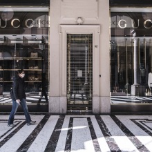 Γυναίκα με μάσκα περπατάει έξω από ένα κλειστό κατάστημα Gucci