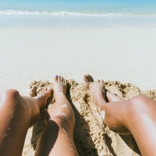 Γυναικεία πόδια στην άμμο παραλίας