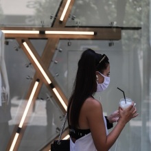 Μία κοπέλα με μάσκα και καφέ