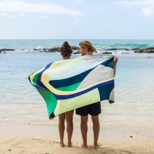 Άντρας και γυναίκα στέκονται με γυρισμένη πλάτη όρθιοι σε παραλία, τυλιγμένοι με μια πετσέτα