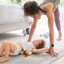 Γυναίκα γυμνάζεται στην κρεβατοκάμαρα δίπλα σε μωρό ξαπλωμένο στο πάτωμα