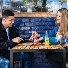 Άντρας και γυναίκα κάθονται σε τραπέζι σε εξωτερικό χώρο με φαγητό και ποτά