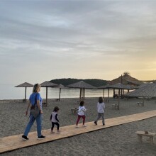 Γυναίκα περπατά σε παραλία με τρία παιδιά