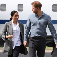 Η Μέγκαν Μαρκλ και ο πρίγκιπας Χάρι περπατούν με φόντο ένα αεροπλάνο
