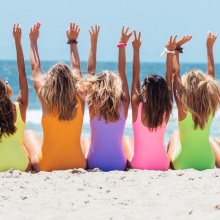 Γυναίκες με μαγιό στην παραλία που σηκώνουν τα χέρια ψηλά