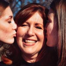 Δύο κόρες φιλάνε τη μητέρα τους στο μάγουλο