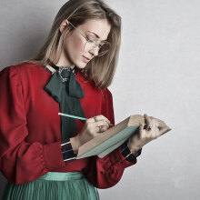 Νεαρή κοπέλα με πράσινη φούστα και κόκκινο πουκάμισο σημειώνει σε βιβλίο