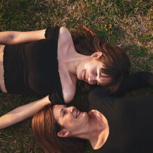 Δύο γυναίκες με μαύρα ρούχα ξαπλωμένες στο γρασίδι αντικριστά