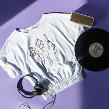 Αντικείμενα (μπλουζάκι, δίσκος βινυλίου, ακουστικά, ηχείο) ακουμπισμένα σε μωβ φόντο