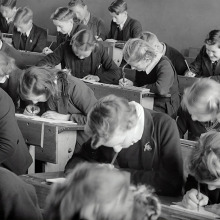 Ασπρόμαυρη φωτογραφία μαθητών σε θρανία να γράφουν διαγώνισμα