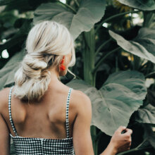 Ξανθιά γυναίκα γυρισμένη πλάτη με μαζεμένα μαλλιά σε χαμηλό κότσο