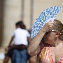 Γυναίκα κρατά στο κεφάλι της την βεντάλια της για να προφυλαχτεί από τον ήλιο