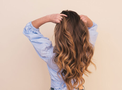 woman wearing gray dress shirt standing near white wall