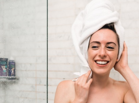 Κοπέλα με πετσέτα στα μαλλιά και το σώμα βγαίνει από το ντους