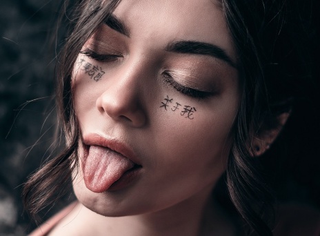 Πορτραίτο μελαχρινής κοπέλας με κλειστά μάτια και τη γλώσσα έξω