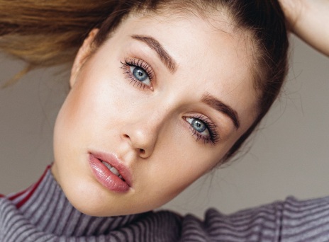 Γυναικείο πρόσωπο με μπλε μάτια και καστανά μαλλιά πιασμένα αλογοουρά