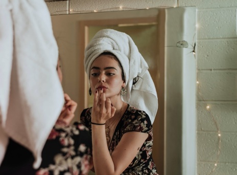 Κοπέλα με πετσέτα στα μαλλιά κοιτιέται στον καθρέφτη