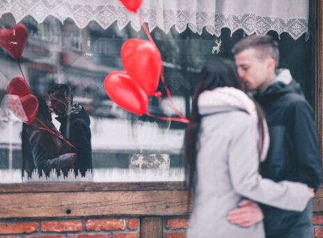 Ζευγάρι μπροστά σε βιτρίνα κρατάει μπαλόνια σε σχήμα καρδιάς