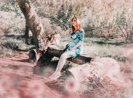 Έγκυος γυναίκα κρατά την κοιλιά της σε δάσος