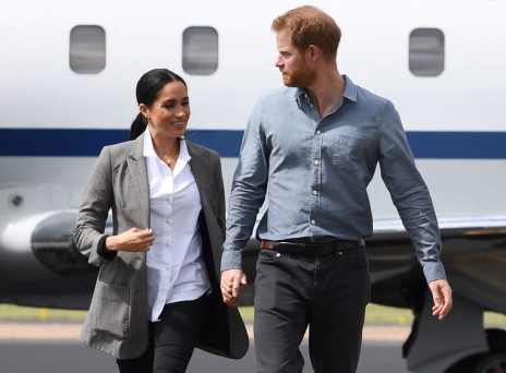 Η Μέγκαν Μαρκλ και ο πρίγκιπας Χάρι περπατούν με φόντο ένα αεροπλάνο