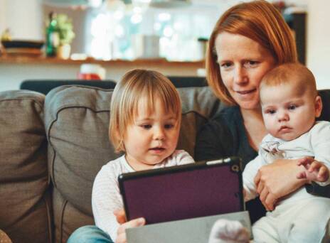 Μια μητέρα κάθεται στον καναπέ αγκαλιά με τα δύο παιδιά της