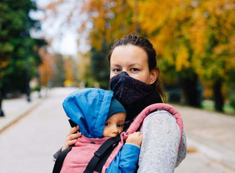 Γυναίκα με μάσκα κρατάει μωρό αγκαλιά