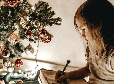 Μικρό κοριτσάκι δίπλα στο χριστουγεννιάτικο δέντρο