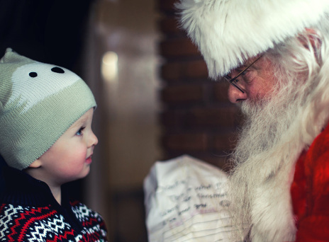 Ένα μικρό παιδάκι στέκεται μπροστά από τον Άγιο Βασίλη
