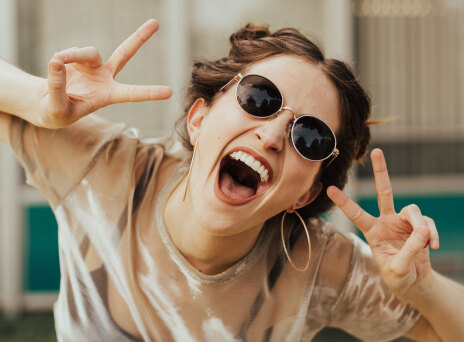 Κοπέλα με γυαλιά ηλίου που γελάει στην κάμερα