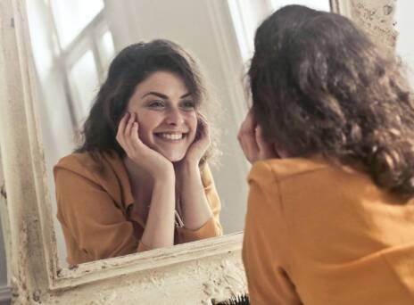 Κοπέλα που κοιτάει στον καθρέφτη και χαμογελάει