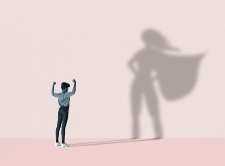 Εικονογράφηση γυναίκα που η σκιά της στον τοίχο έχει τη πόζα σουπερήρωα (μετα χέρια στη μέση και την κάπα να ανεμίζει)